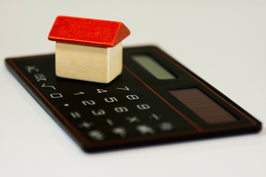 casa em miniatura em cima de uma calculadora, representando a rentabilidade de alugar e vender imóvel