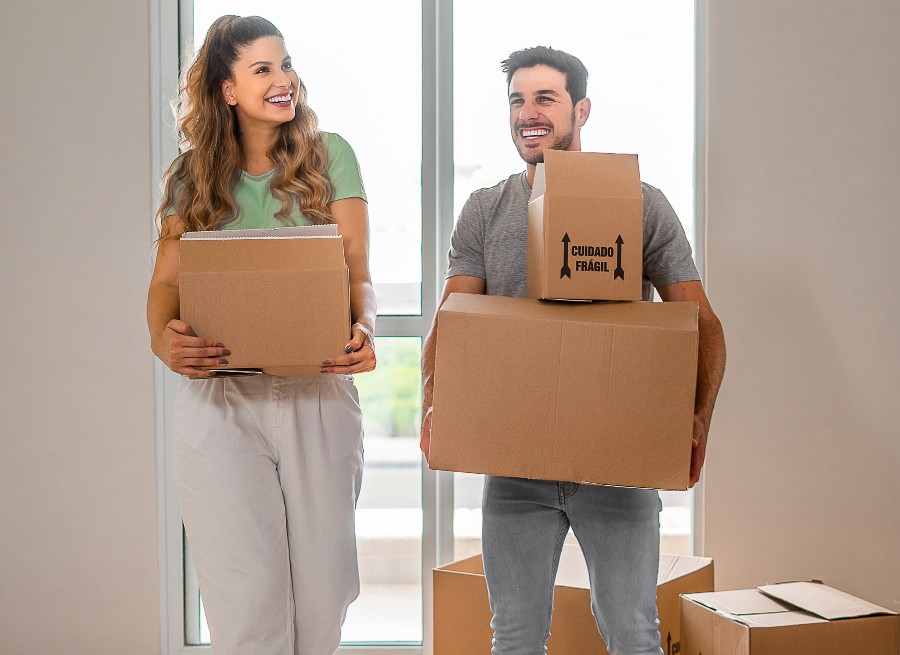 casal com caixas de mudanças no novo imóvel após entender como como comprar um apartamento na planta