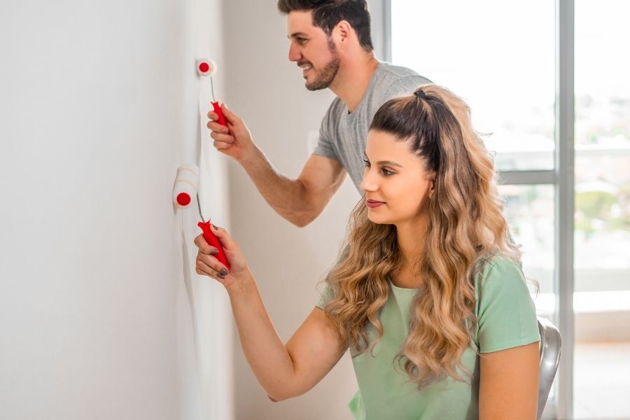 Casal pintando parede para melhorar valor do imóvel